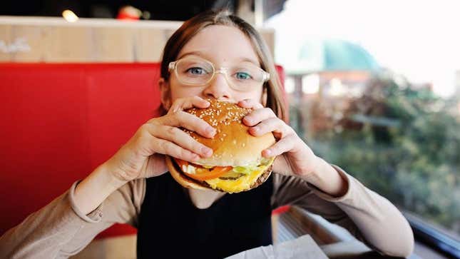 Child eating hamburger at restaurant with allergies