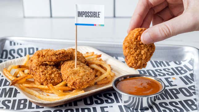 Tray of Impossible Chicken Nuggets and fries, with one nugget being dipped into sauce