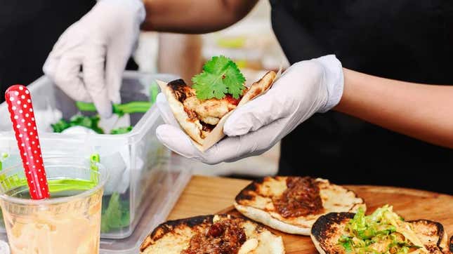 hands in gloves preparing tacos at quick service restaurant